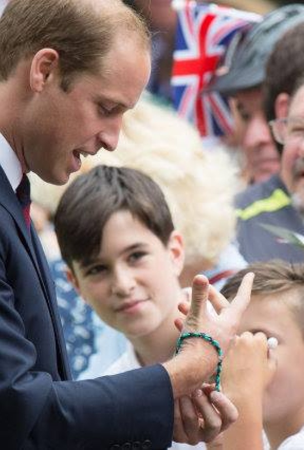 الأمير ويليام يجرب أحد الأساور التي قدمت له من أحد المعجبين اللذين تجمعوا للقائه في حديقة Coventry's War Memorial