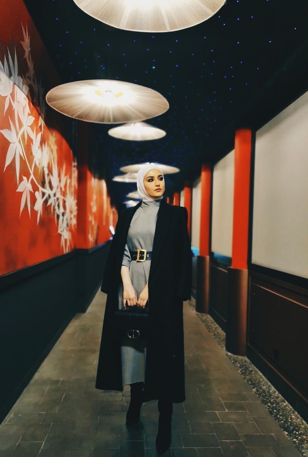 دلال الدوب بدت بغاية الأناقة بالفستان الرمادي الميدي مع المعطف الاسود الراقي