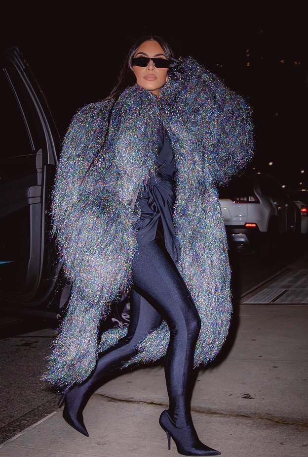 أطلت كيم بالمعطف الطويل مع الشراريب الفضية وتحته التوب الأسود والليغينغ الموصول بالجزمة