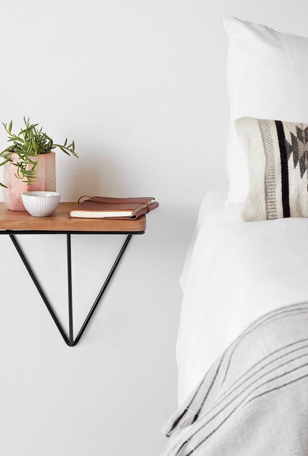 رف خشبي بسيط يستعيض عن الطاولة الجانبية للسرير