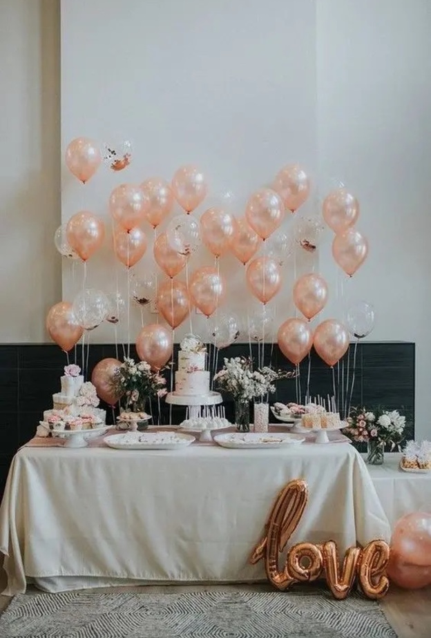 ديكور أنيق لطاولة زفاف بالبالونات البيضاء ونباتات الزينة الخضراء والزهور