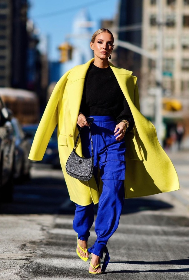 تألقت بالمعطف الأصفر الذي  نسّقته مع التوب الأسود والبنطلون الواسع باللون الأزرق