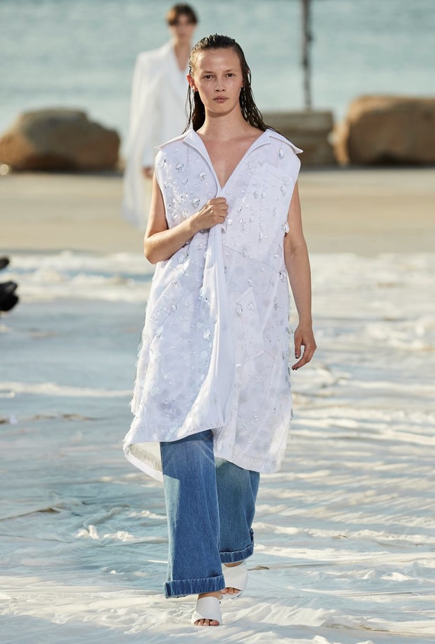 نسّقت دار Peter Do البنطلون الجينز الواسع مع الجاكيت الطويلة من دون أكمام ومزيّنة بالشكّ