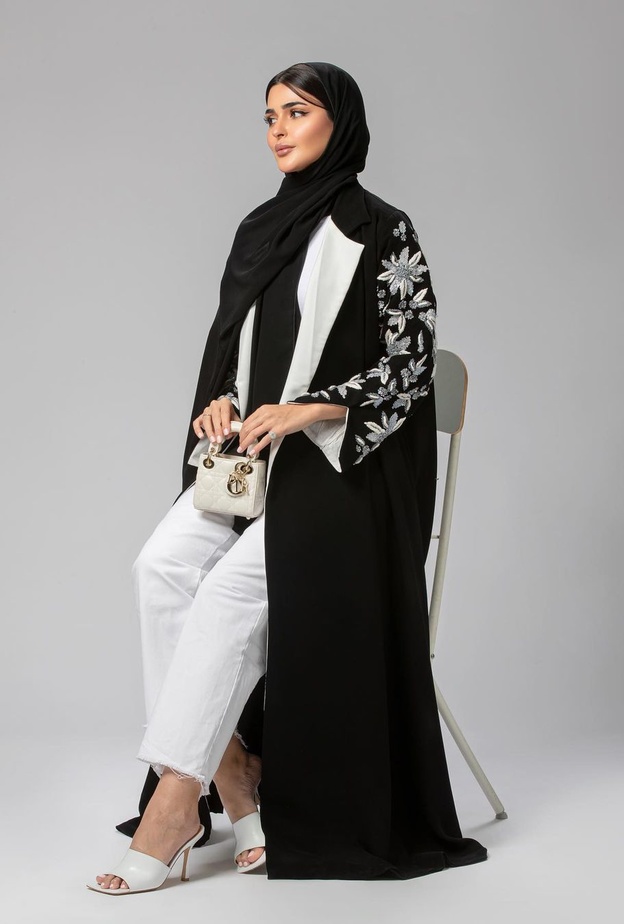 حنين الصيفي فبدت أنيقة وعصرية بجمعها بين العباية السوداء الطويلة والبنطلون الدنيم الأبيض
