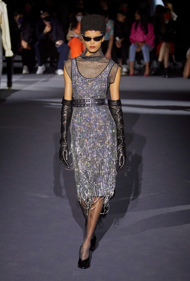 فستان ميدي باللونين الأسود والفضي ذو لمسات معدنية وبرّاقة، وحزام جلدي أسود، وقفازات