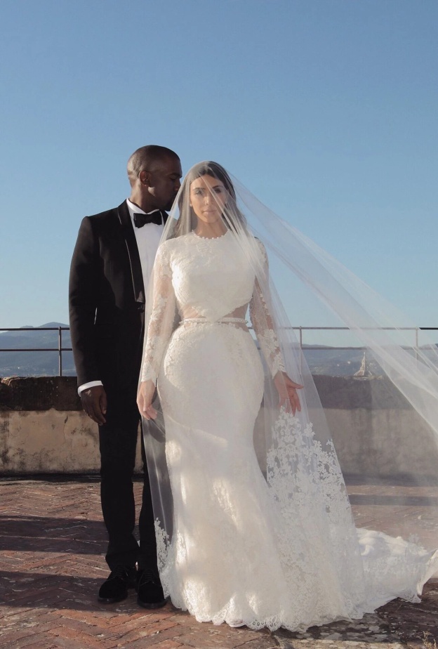 ظهرت كيم في حفل زفاف بفستان زفاف مبهر طويل الأكمام ومفتوح الظهر، مصنوع من قماش الدانتيل