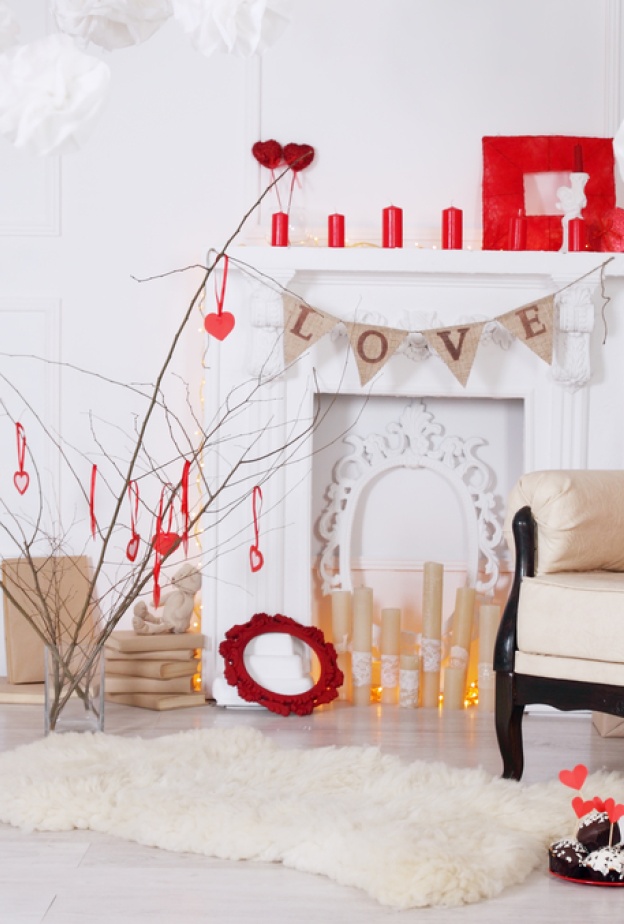 مدفأة مزينة بالشموع الحمراء وزينة بكلمات حب رقيقة