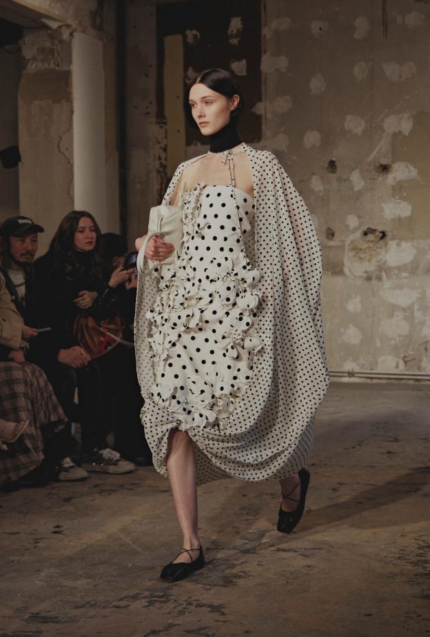 فستان من Rokh بقصة غنيّة بالطيات، يجمع بين اللون الأبيض الأساسي والنقشة المرقطة بالأسود، لإطلالة رومانسية كلاسيكية