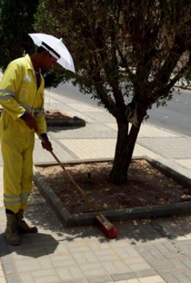 عمال النظافة يرتدون المظلات الشمسية