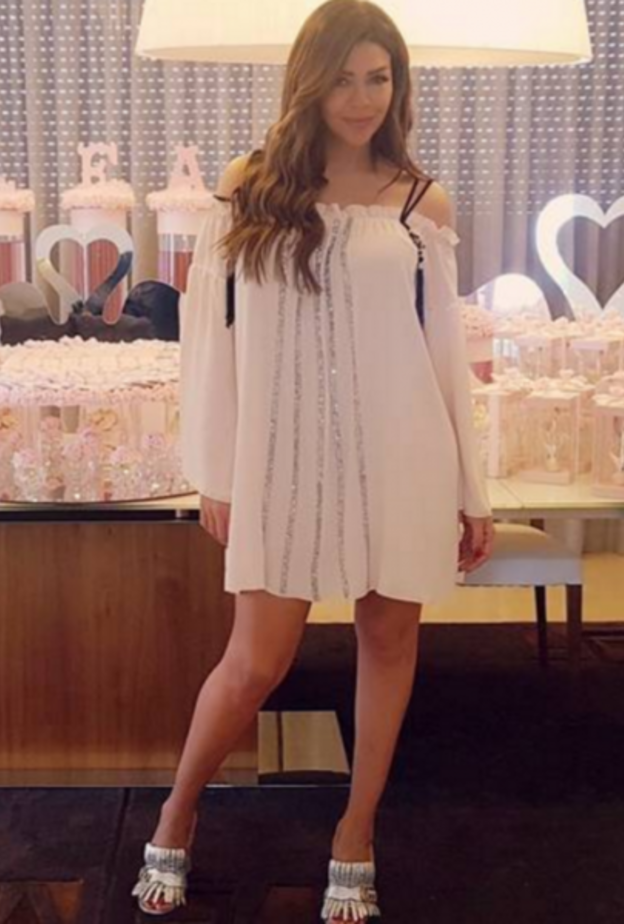 فستان أبيض قصير مكشوف الأكتاف تألقت به أمل بوشوشة بعد الولادة ونسقته مع حذاء فضي من غوتشي