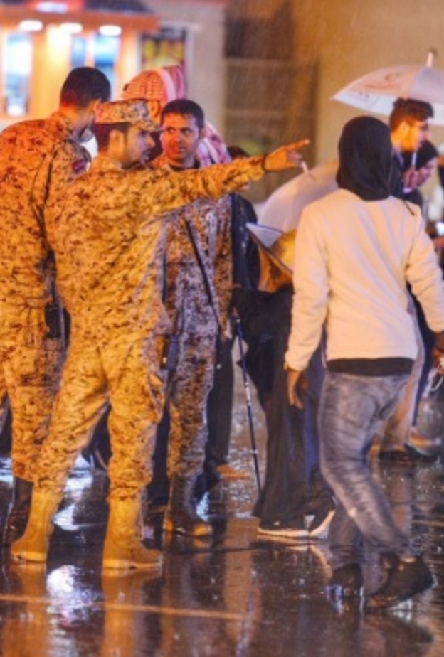 صورة مؤثرة..رجل أمن سعودي يحمي مسنة من الأمطار بملابسه الخاصة