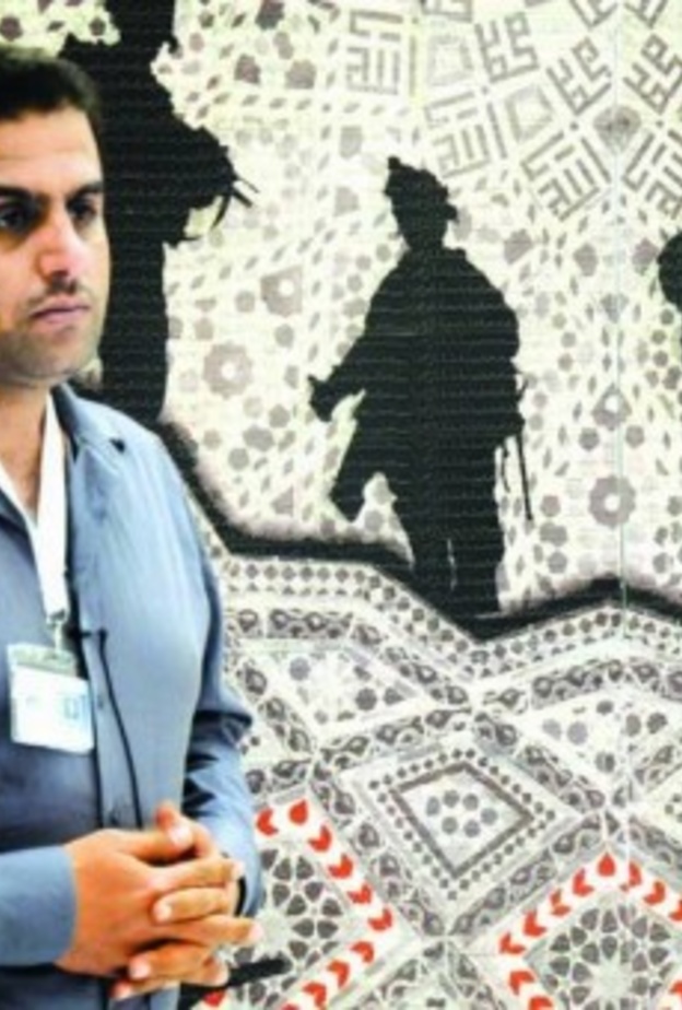 الفنان بجانب إحدى لوحاته