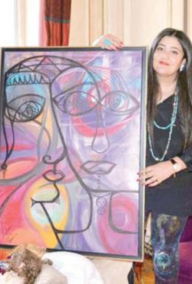 الفنانة مع احدى لوحاتها