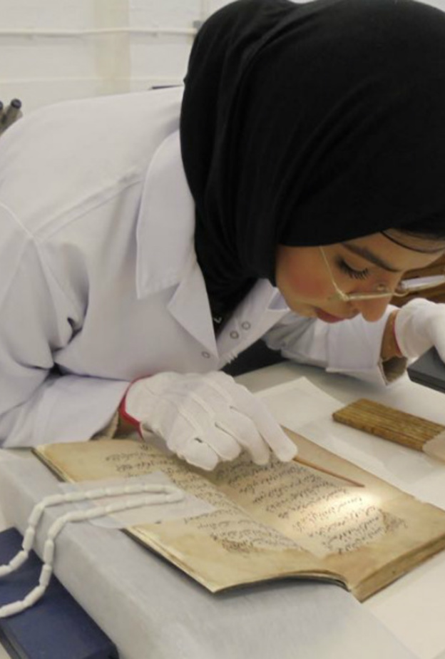 فاطمة الضيف اثناء اداء عملها بترميم الأعمال الفنية