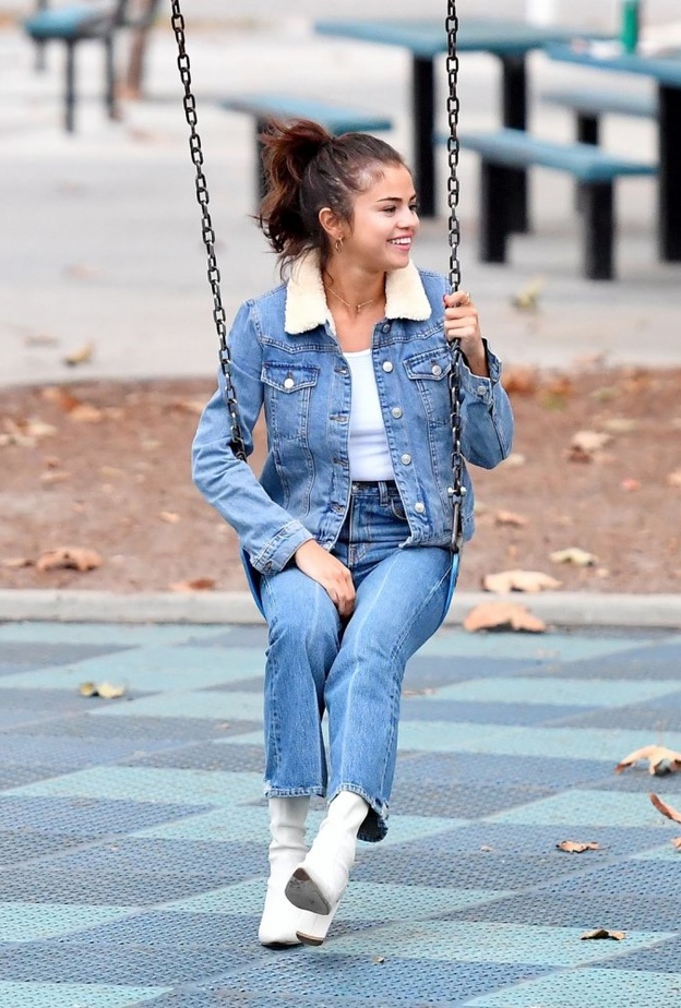 لوك صباحي اختارت فيه سيلينا غوميز معطف طويل باللون الرمادي ونسقته مع حذاء أبيض وشنطة يد من كوتش