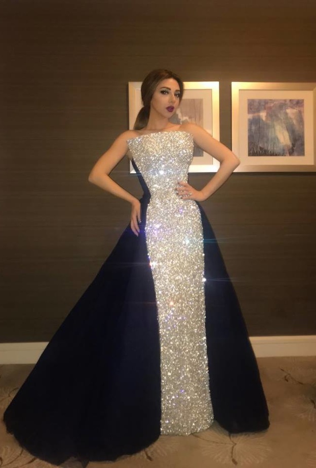 جمع الفستان بين قماشين الاول فضيّ برّاق والثاني جاء باللون الكحلي من الخلف وعند الجانبين