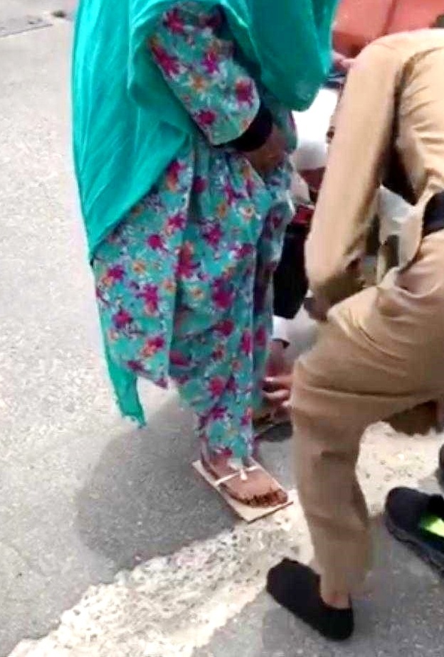 الحاج يساعد الحاجة المسنة على تثبيت الحذاء الذي صنعته من الورق المقوى