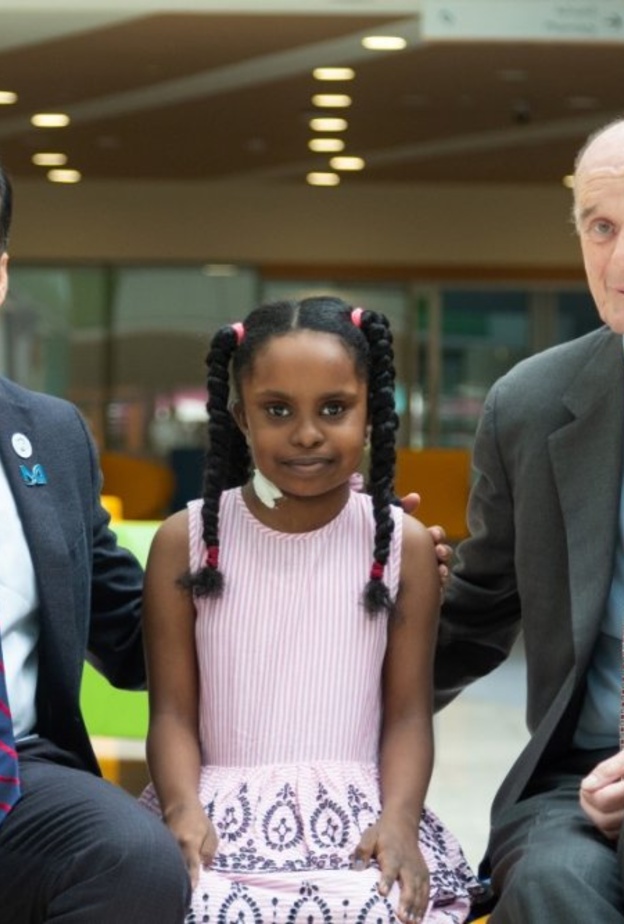 الطفلة السودانية وسط أسرتها والفريق الطبي المعالج لها 