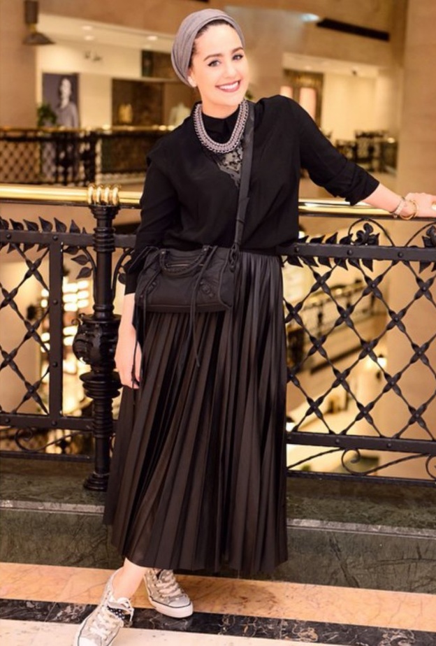 السويت شيرت السوداء مع التنورة البليسيه الجلدية بأسلوب دينا طوكيو.