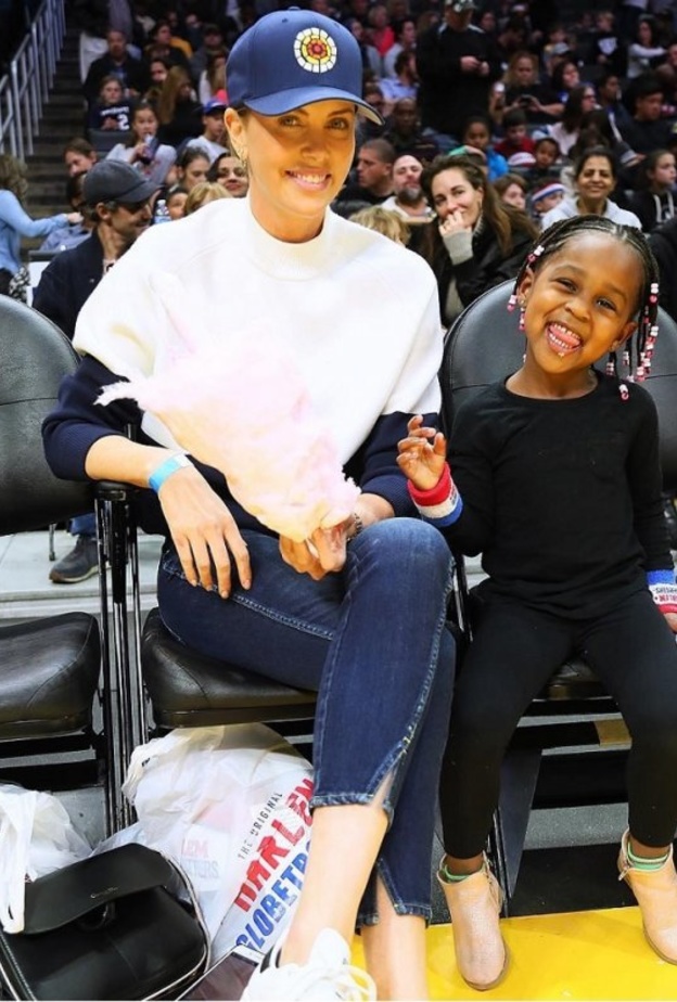 تشارليز ثيرون تبتسم للكاميرا مع ابنتها أوغست أثناء حضورهما مباراة لكرة السلة