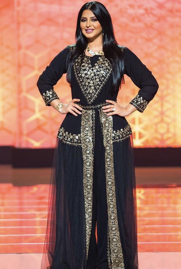 إطلالة كيب باللون الأسود مزدانة بنقوش وتطاريز بنفس لون الفستان على الصدر وعلى شكل حزام خصر