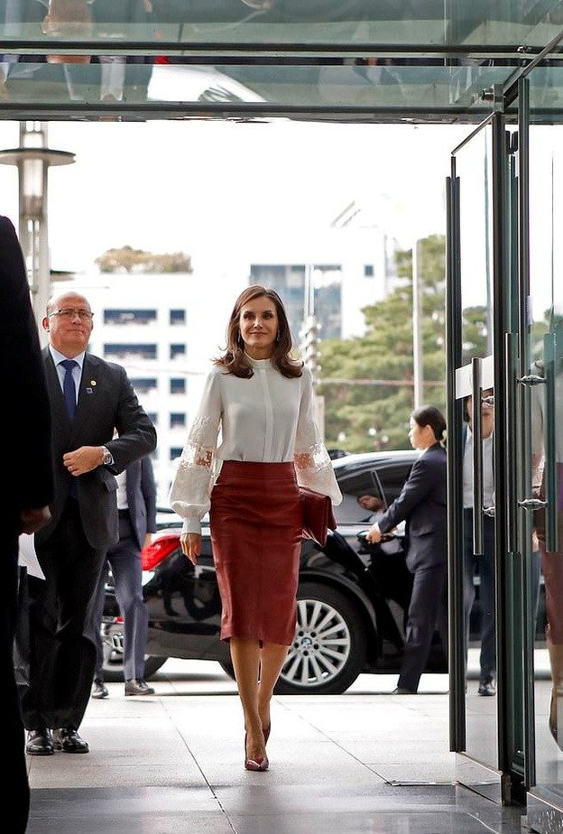 إختارت قميصاً أبيض نسّقت معه تنورة ميدي من قماش الجلد الأحمر