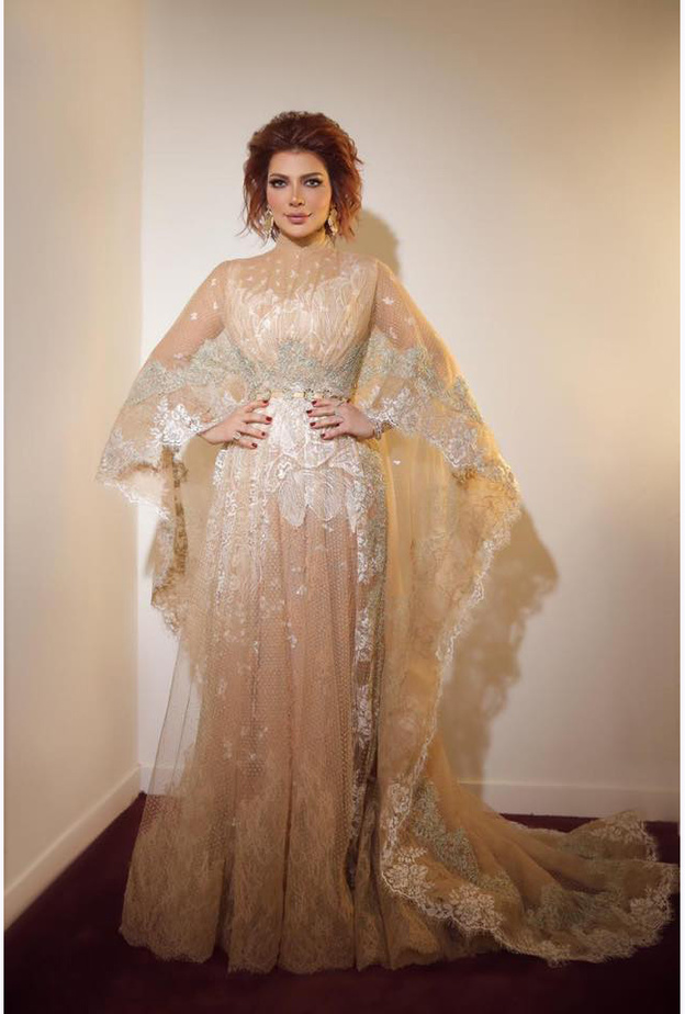  الفستان جاء بياقة عالية، وبأكمام واسعة كالكاب فإنسدلت بإنسيابية على الأرض