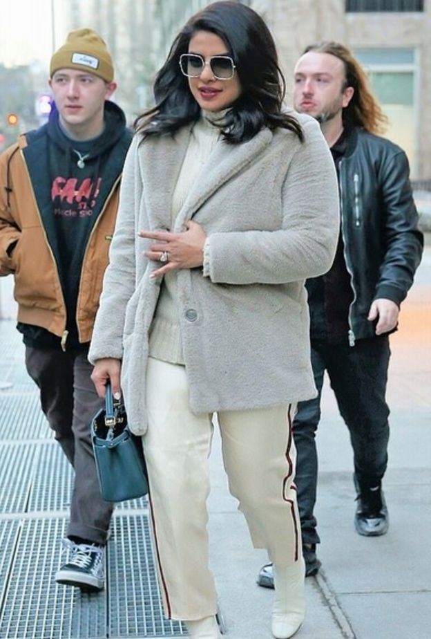 أطلت بسروال من قماش الساتان مع كنزة ومعطف قصير من الفرو الناعم باللون الرمادي الفاتح