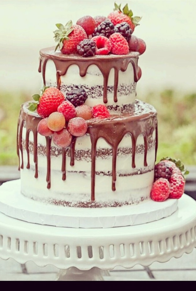 كعكة الزفاف العارية بصوص الشوكولاتة البنية السائلة والمزينة بأشكال الورود ونباتات الزينة الخضراء