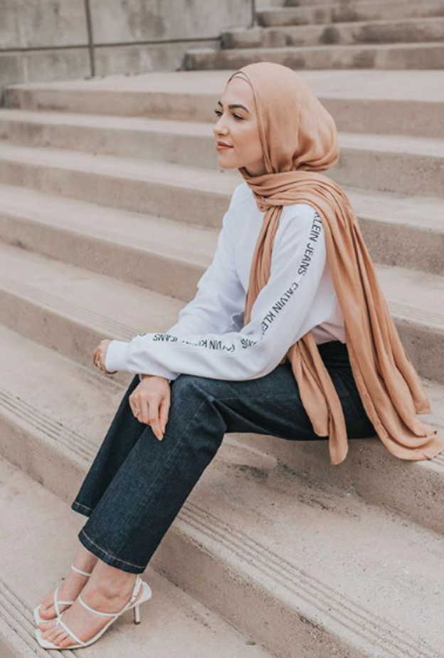 نسّقت لينا صنوبر الجينز الداكن مع التوب الشبابي الأبيض والصندل العصري والناعم