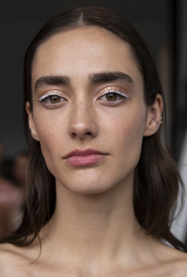 استوحي من Pamella Roland الآيلاينر الأبيض الناعم الذي يزين الجفون البرونزية