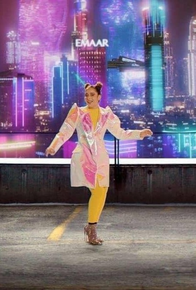 أطلت باللون الأصفر ونسّقت فوقه المعطف الميدي بقماش ميتاليكي وبألوان قوس القزح المتغيّرة