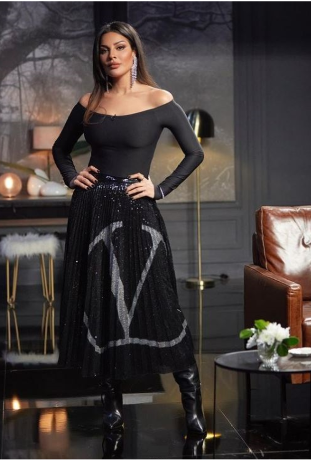 إختارت تنورة ميدي من ماركة فالنتينو  تميّزت بالترتر اللامع باللون الأسود مع لوغو الدار