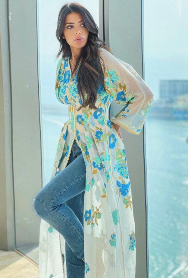 نسقت القفطان الأبيض الذي تميّز بقماشه الشفاف والمزيّن بالورود الزرقاء مع البنطلون الدنيم