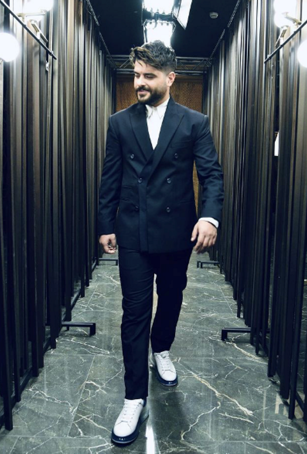 بالبدلة السوداء مع الجاكيت بقصة الأزرار المزدوجة والتي نسّقها مع الحذاء الرياضي