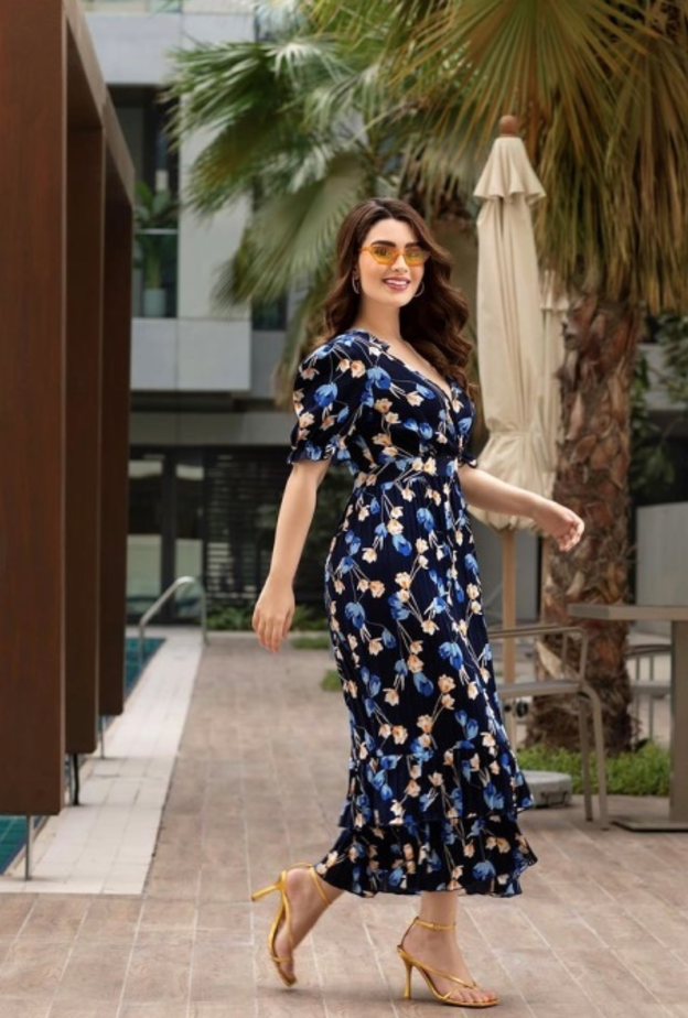 الفستان الأسود الذي تميّز بأكمام القصيرة المنفوخة ومزيّن بنقشة الورود باللونين الأزرق والبيج ونسّقت معه الصندل الأصفر