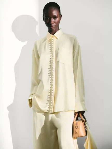 قميص ساتان بقصّة واسعة مع أزرار لؤلؤية باللون الأصفر الزبدي من Stella Mccartney