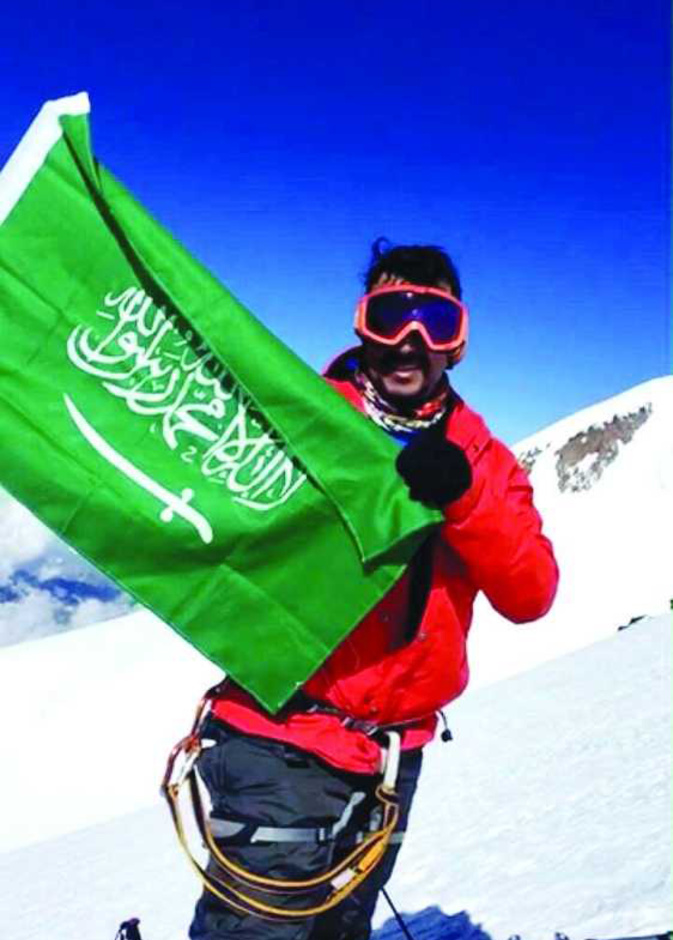 خالد الغامدي يرفع علم المملكة وعلم الرؤية 2030.