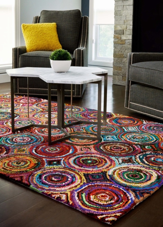 على الأرضية الخشب و اللون الرمادي للكنب لا شيء أجمل من سجادة ملونة بألوان مشرقة