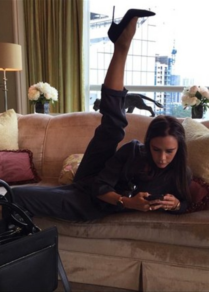 تقوم فيكتوريا بيكهام بتمديد ساقها مرتدية الكعب العالي فيما تتصفح جوالها 