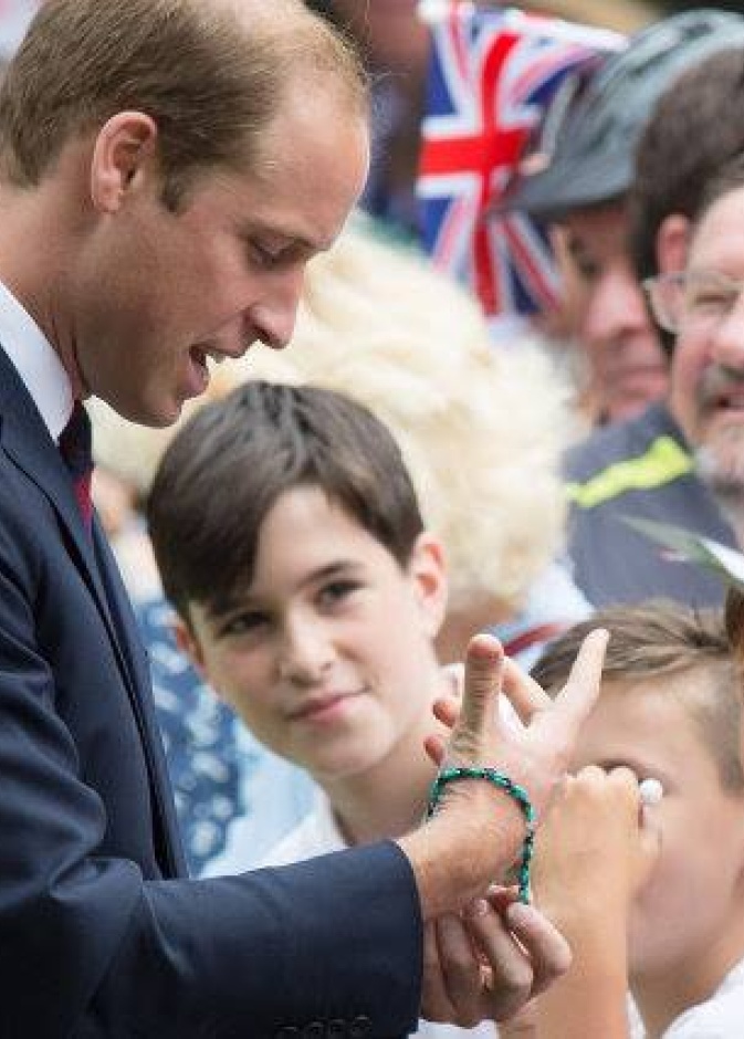 الأمير ويليام يجرب أحد الأساور التي قدمت له من أحد المعجبين اللذين تجمعوا للقائه في حديقة Coventry's War Memorial