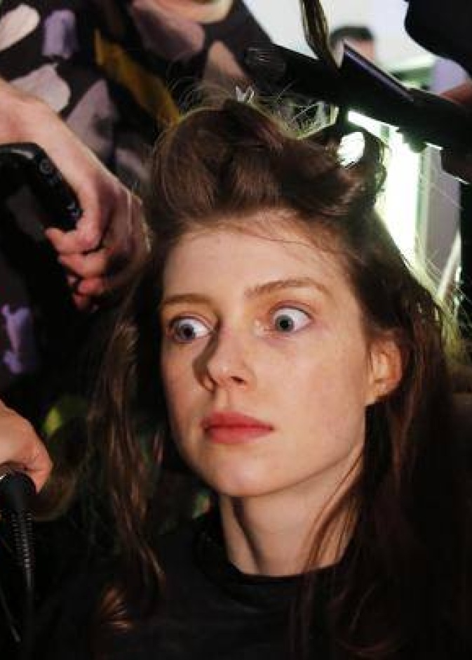 عارضة أزياء تبدو منبهرة أثناء تصفيف شعرها من قبل أكثر من خبير تجميل خلال عروض الأزياء في لندن!