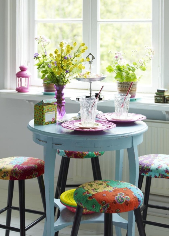 طاولة صغيرة بدرجة فاتحة من الأزرق مع كراسٍ بسيطة منجدة بألوان متفاوتة على الطراز الهندي