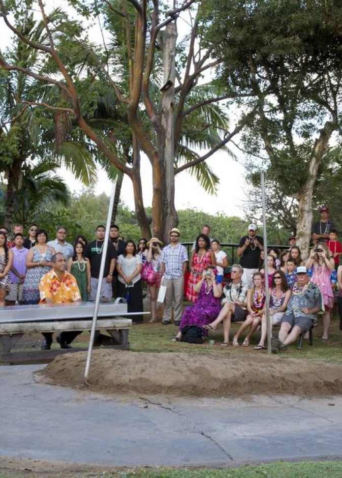 Attractive young men in traditional Hawaiian dress play seashell