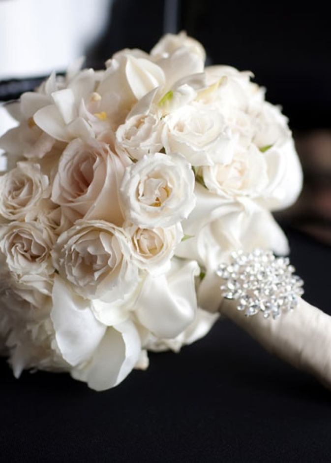 بوكيه تحتوي على خصل من أزهار بيضاء غاية في النعومة ،مزينة بأحجار الكريستال علة مسكتها