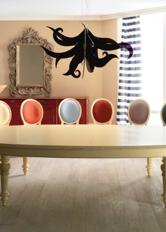 طاولة ذات شكل بيضاوي باللون الكريمي وعدد هائل من الكراسي الملونة بألوان مختلف