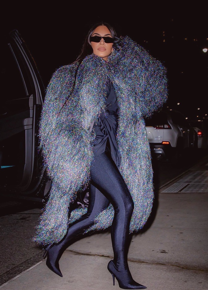 أطلت كيم بالمعطف الطويل مع الشراريب الفضية وتحته التوب الأسود والليغينغ الموصول بالجزمة