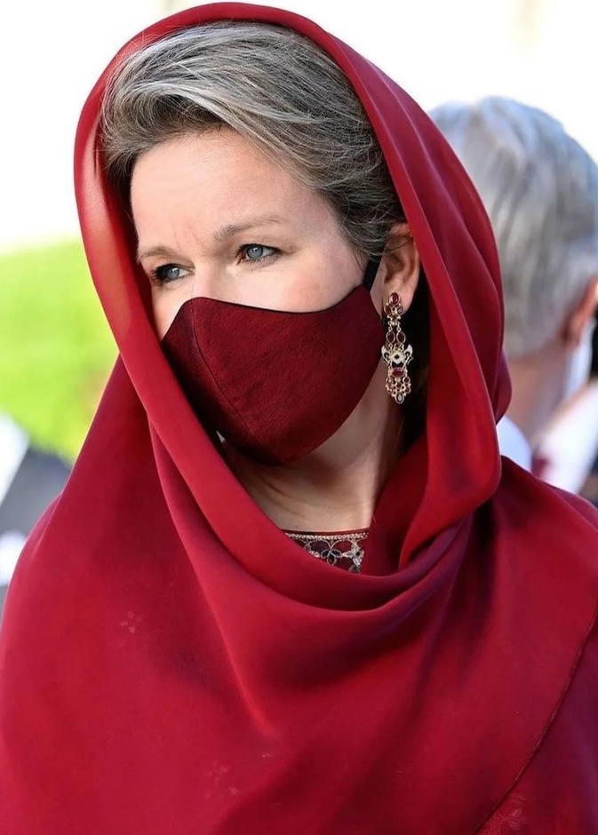 ملكة بلجيكا بإطلالة حمراء وغطاء رأس خلال زيارة مسجد السلطان قابوس