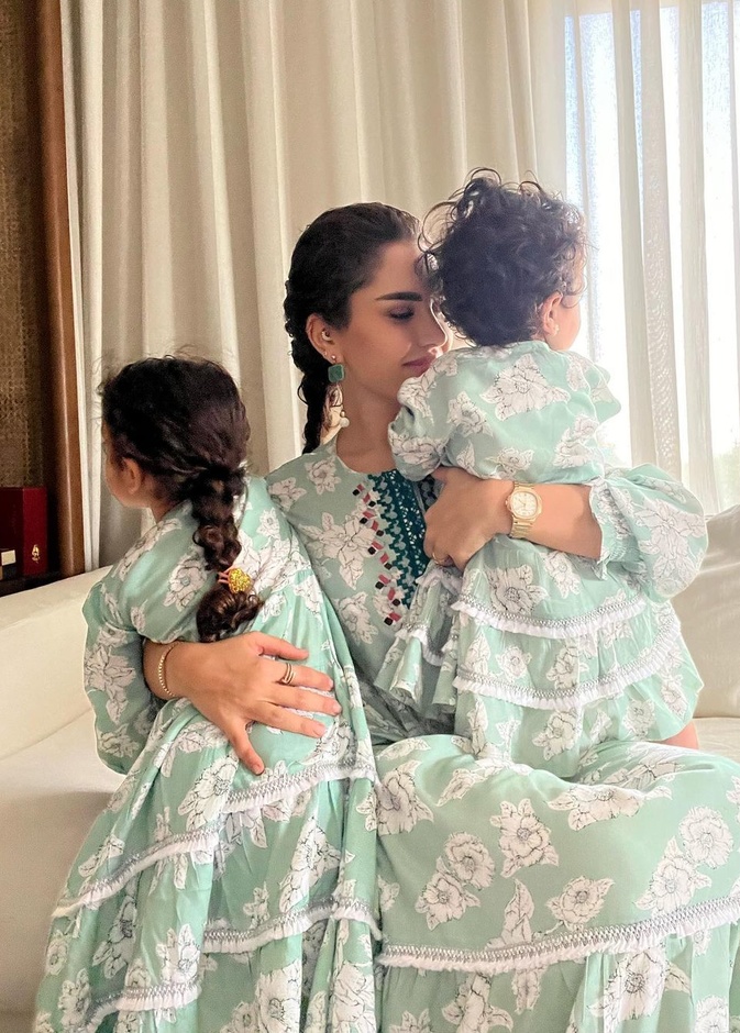 نجود الرميحي وابنتيها بالقفاطين باللون الأزرق الباستيل مع الورود باللون الأبيض