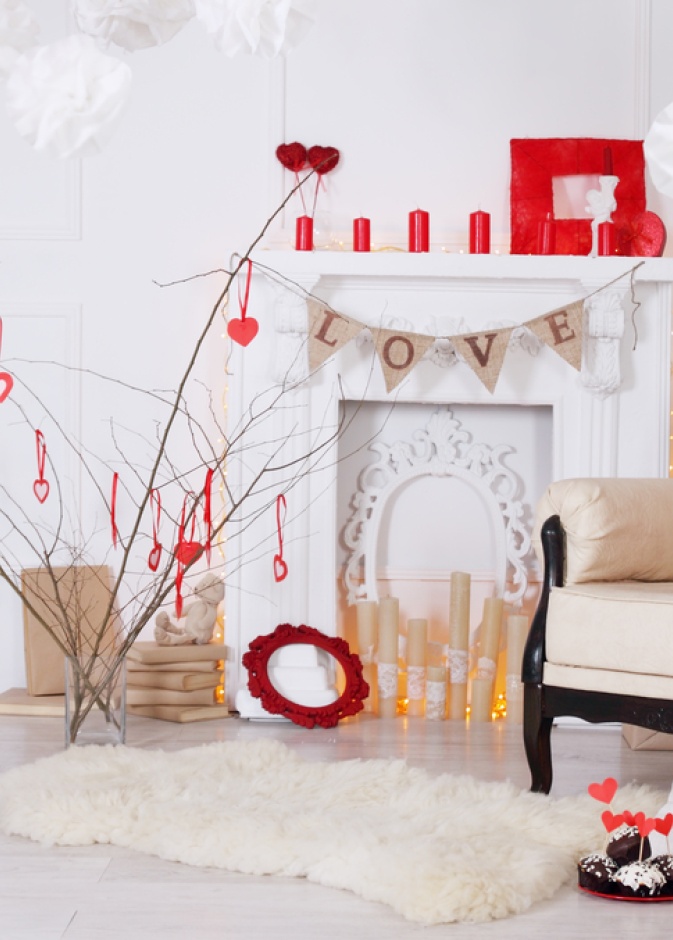 مدفأة مزينة بالشموع الحمراء وزينة بكلمات حب رقيقة